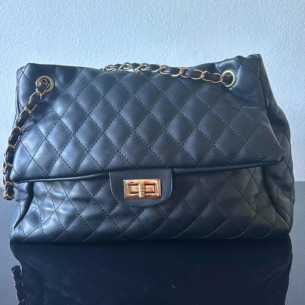 Stylish black shoulder bag with gold and leather straps. Medium size.